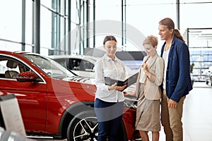 Car sales manager telling about the features of the car to the customers at the dealership