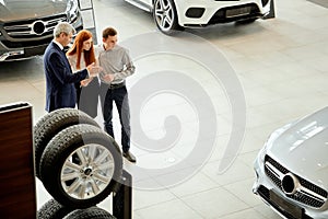 Car sales manager telling about the features of the car to the customers at the dealership