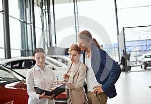 Car sales manager telling about the features of the car to the customers at the dealership