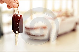 Car sales showroom and person holding car key in hands