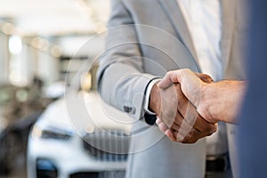 Car salesman and client handshake