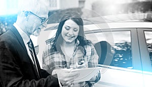 Car salesman giving explanations on tablet to young woman; multiple exposure