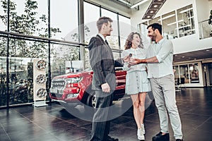 Its good choice!Car salesman is giving the key of the new car to the young attractive owners