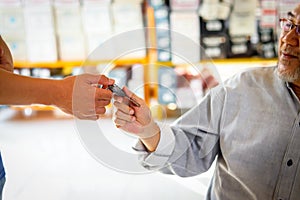 Car salesman giving key to new owner at showroom, young agent giving car key to senior customer after signed contract form