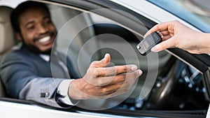 Car salesman giving keys to happy man