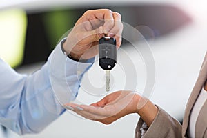 Car salesman handing car keys to woman