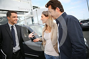 Car salesman handing keys to clients