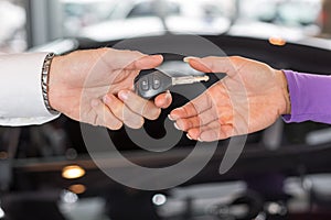 Car salesman handing over car keys in dealership