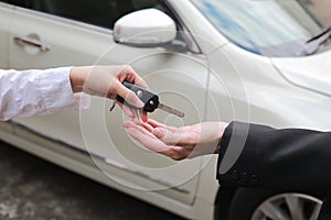 Car salesman handing over the keys for a new car to young businessman.