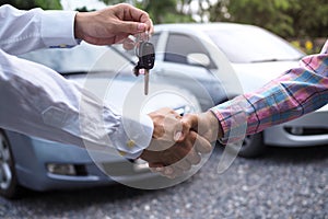 The car salesman is handing over the keys to the buyer after the lease has been agreed