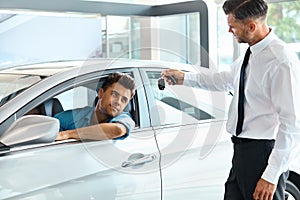 Car Salesman Handing over new Car Key to Customer at Showroom