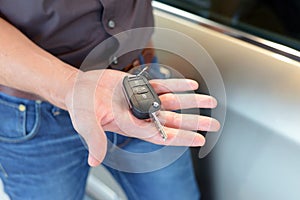 car salesman hands over the car key in the car dealership to customers