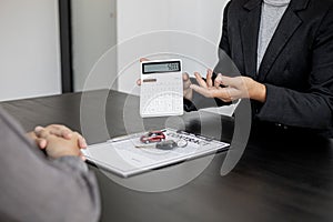 A car salesman holds a white calculator used to calculate.