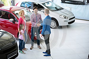 Car salesman showing new vehicle to customers