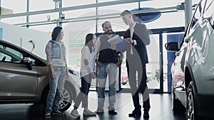 Car salesman shows a young family information about their new car