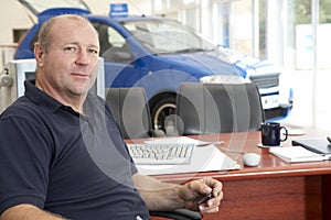 Car salesman sitting in showroom