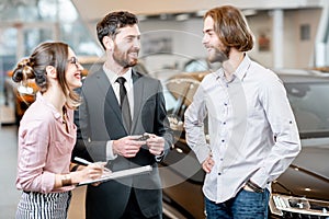 Car salesman wth young couple in the showroom