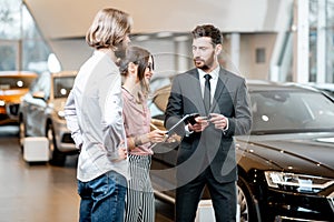 Car salesman wth young couple in the showroom