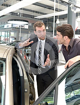 Car salesmen and customers talk about the technology of a car in