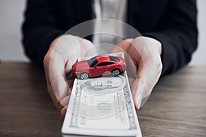 Car salespeople are submitting cash with model cars to customers with concept of buying a new car photo