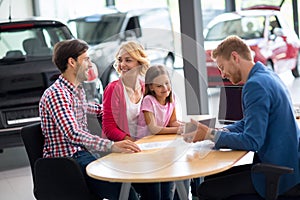 Car salesperson demonstrating new car to family photo