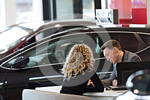 Car salesperson discussing with customer in showroom