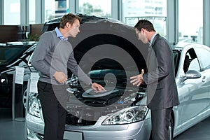 Car salesperson explaining about car's engine to customer