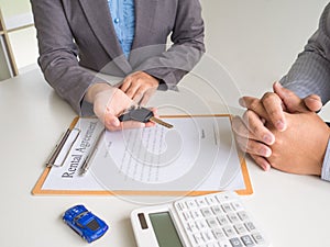 Car saleswoman giving the key to customer and signed a car rental service lease contract