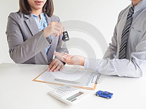 Car saleswoman giving the key to customer and signed a car rental service lease contract