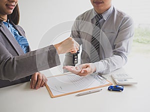 Car saleswoman giving the key to customer and signed a car rental service lease contract