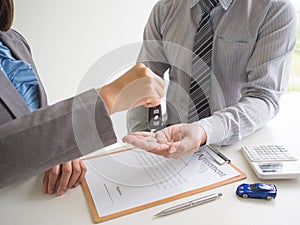 Car saleswoman giving the key to customer and signed a car rental service lease contract