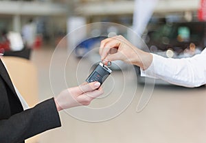 Car saleswoman handing over keys for a new car to young woman