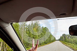 Car salon, steering wheel, mirror and view on landscape with road and nature at sunny summer or autumn day. Female traveller and