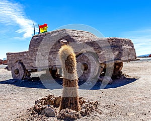 Car sculpture, San Pedro Cactus and Bolivian Flag in salt flat Salar de Uyuni, Bolivia