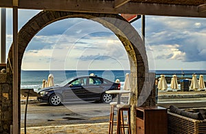 Car on seascape background, cafe and tavern on beach, Crete, Greece. Travel destinations concept. Summer recreation and journey