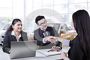 Car seller shaking hands with his customer