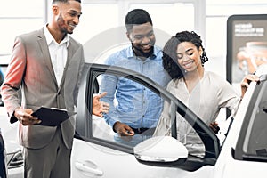 Car Selling Manager Showing Luxury Car To Buyers In Dealership