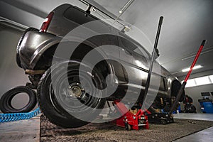 Car service lifting car and changing wheels using trolley jack. A spring hose to a pneumatic tool. Tire repair, wheel replacement