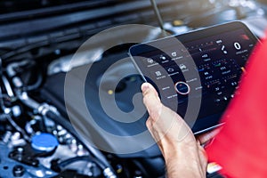 Car service mechanic using digital tablet with diagnostics software to check engine condition. vehicle inspection