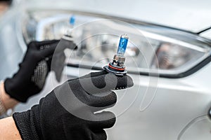 Car service men holding halogen h7 lamp for change in headlight