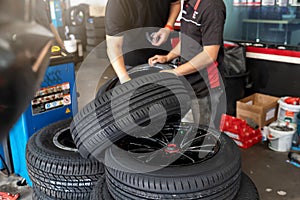 Car service, repair and maintenance concept - auto mechanic man changing tire in auto repair shop