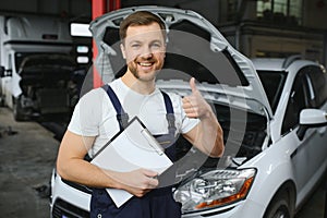 car service, repair, maintenance and people concept - happy smiling auto mechanic man or smith with clipboard at