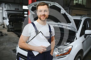 car service, repair, maintenance and people concept - happy smiling auto mechanic man or smith with clipboard at