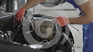 Car service, repair, maintenance and people concept - mechanic man working at workshop. Proffesional car maintenance at