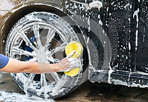 Car service washing car wheels with yellow sponge at outdoor