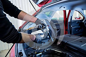 A car service worker cleans interiror with a special foam generator