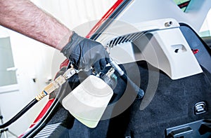 A car service worker cleans interiror with a special foam generator