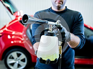 A car service worker cleans interiror with a special foam generator