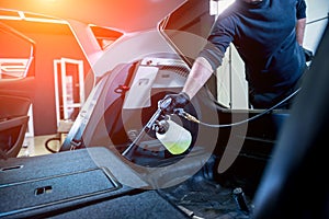 A car service worker cleans interiror with a special foam generator