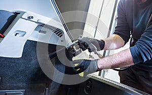 A car service worker cleans interiror with a special foam generator